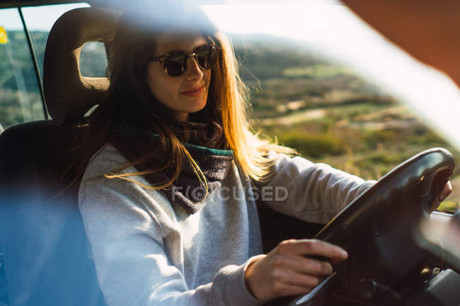 Mulher em óculos de sol carro de condução na natureza — Fotografia de Stock