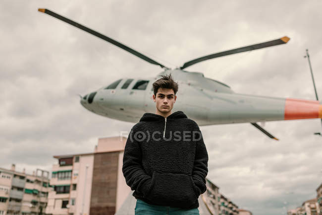 Joven guapo parado en el monumento del helicóptero en la calle de la ciudad - foto de stock