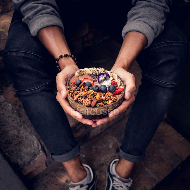 Hands of unrecognizable person holding bowl full of tasty fruits and nuts. — Stock Photo