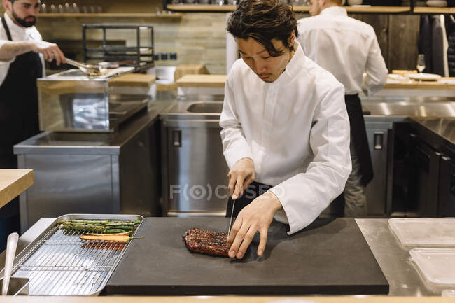 Cocinero cocinando en el restaurante corto de la carne - foto de stock