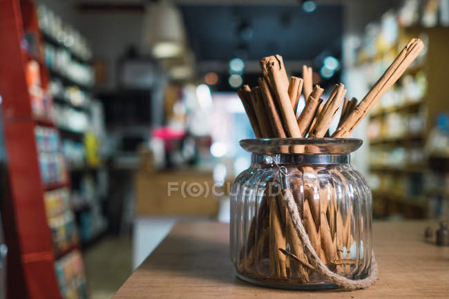 Bâtonnets de cannelle en pot sur la table dans le magasin — Photo de stock