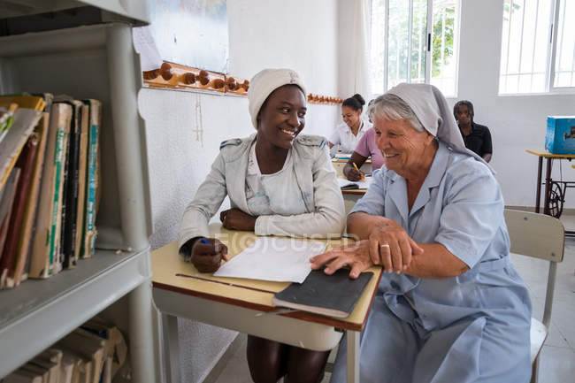 ANGOLA - ÁFRICA - 5 DE ABRIL DE 2018 - Alegres mujeres médicas multirraciales sentadas y sonriendo en clase - foto de stock