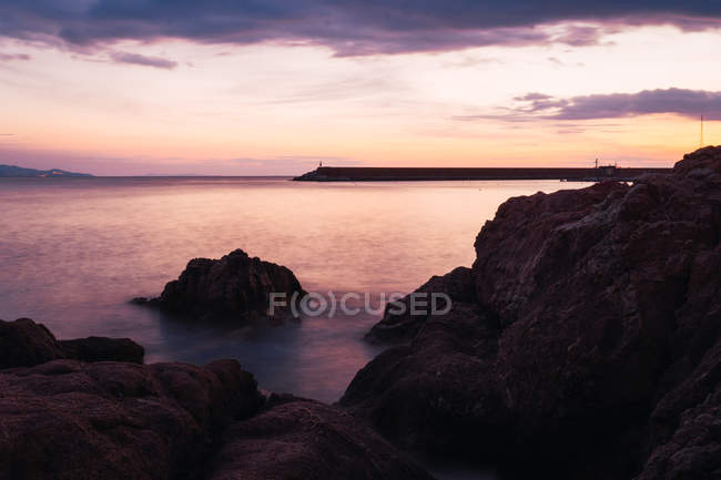 Costa rocciosa e cielo drammatico al tramonto — Foto stock