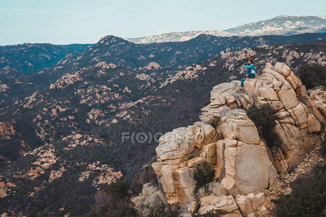 Woman sitting on rock in mountains and looking at view — Stock Photo