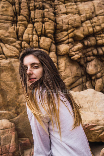 Portrait of young woman posing in front of rough rock — Stock Photo