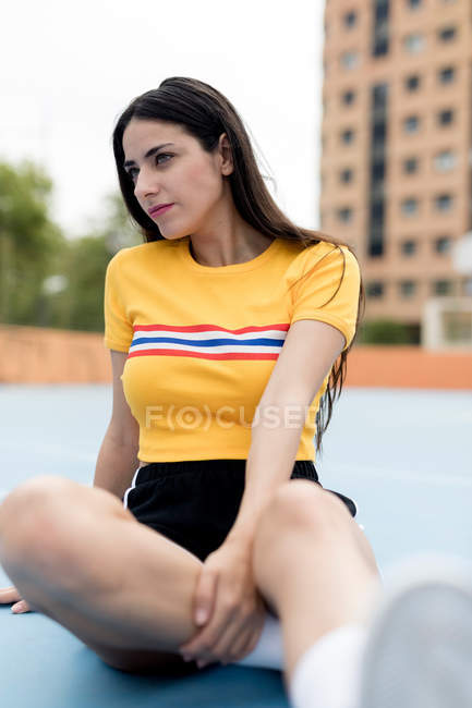Junge Frau sitzt auf Sportplatz — Stockfoto