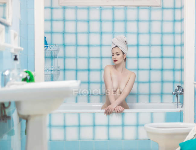 Чуттєвий молодий з рушником на голові сидить у ванній — стокове фото