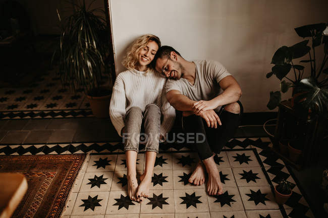 Smiling man and woman sitting on floor at home together — Stock Photo