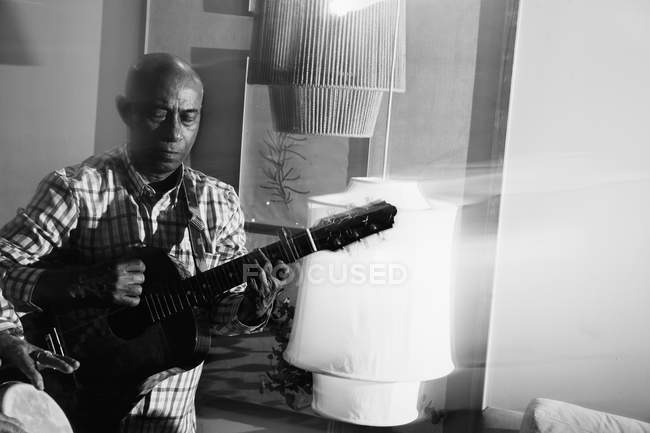 Afrocuban male musician playing guitar in night club, black and white shot with long exposure — Stock Photo