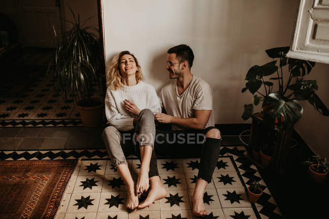 Веселий чоловік і жінка сидять на підлозі і розважаються вдома — стокове фото