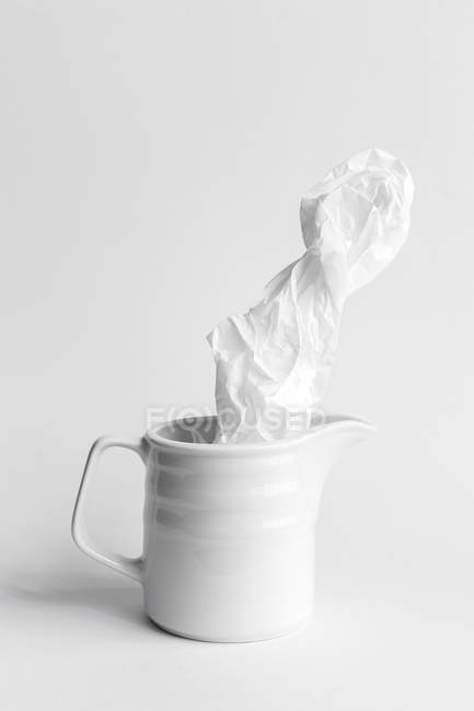 Зморщений папір в керамічному кухоль на білому тлі — стокове фото