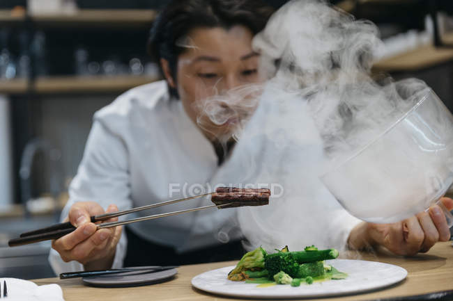 Cuoco cucina in ristorante con piatto di fumo — Foto stock