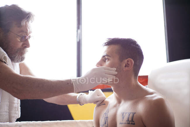 Mãos de médico irreconhecível verificando o olho do boxeador no anel de boxe. — Fotografia de Stock