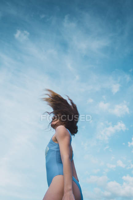 Весела молода жінка в блакитному купальнику стоїть на блакитному небі — стокове фото