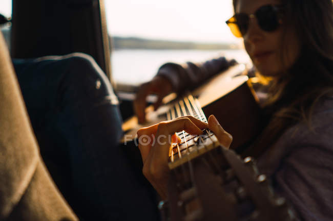 Mulher elegante com guitarra sentado no carro na natureza — Fotografia de Stock