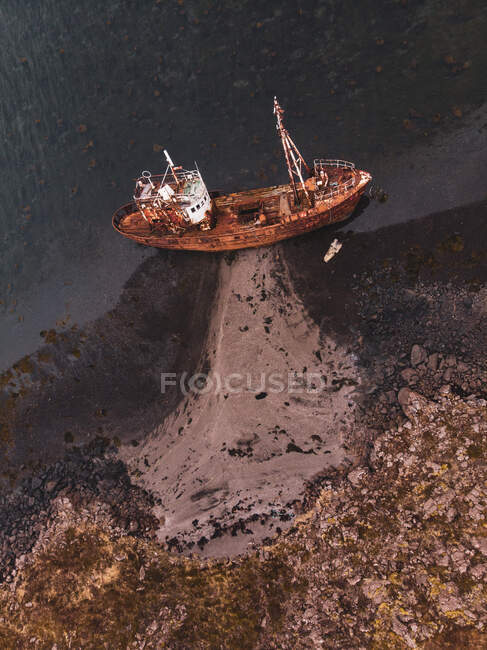 Barco abandonado cerca de costa pedregosa - foto de stock