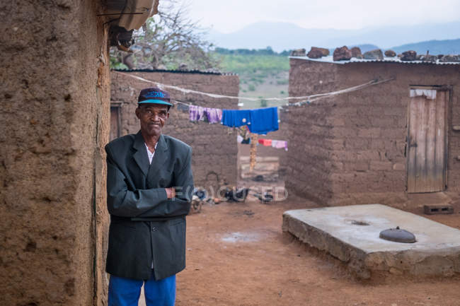 АНГОЛА - АФРИКА - 5 апреля 2018 года - старший черный мужчина со скрещенными руками стоит перед домом — стоковое фото
