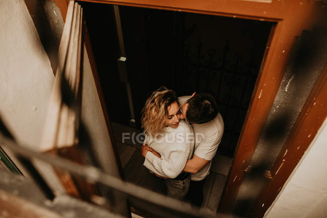 Allegro uomo e donna in piedi e abbracciando alla finestra a casa — Foto stock