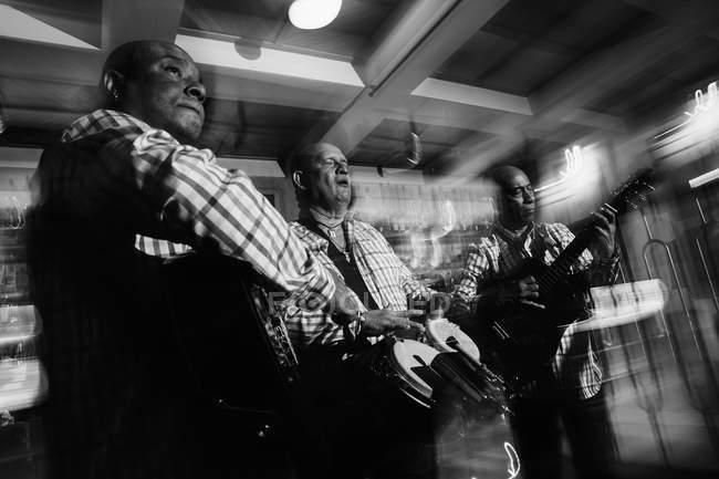 Музичне тріо Куби грає в нічному клубі, чорно-білий постріл з довгим виступом. — стокове фото