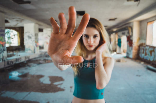 Magra ragazza in piedi in edificio in decomposizione con braccio teso — Foto stock
