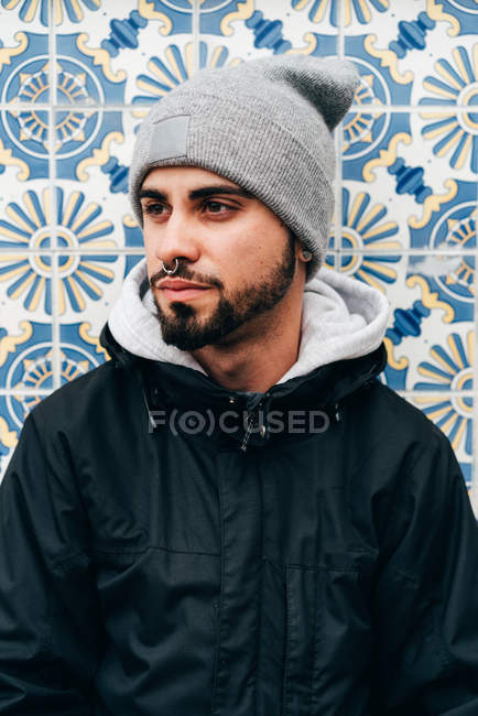 Retrato de turista masculino pensativo em pé na parede com azulejos azuis — Fotografia de Stock
