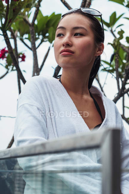 Женщина в халате сидит на улице перед цветущим деревом — стоковое фото