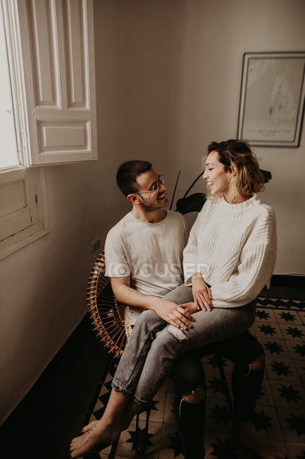 Homem sentado em poltrona com namorada no colo em casa — Fotografia de Stock