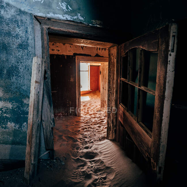 Doorways and interior in old abandoned houses with floor covered with sand. — Stock Photo