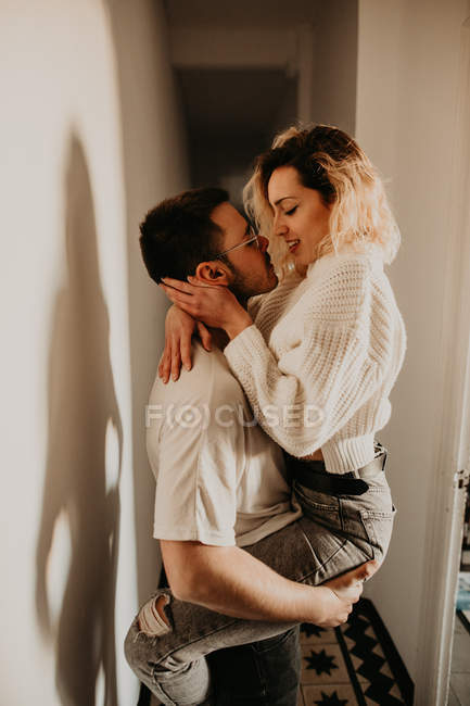Passionate man and woman embracing and kissing at wall at home — Stock Photo