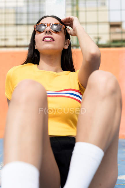 Jeune femme mince dans les lunettes de soleil appuyé sur la clôture — Photo de stock