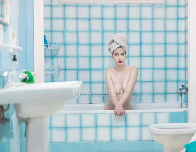 Sensual jovem com toalha na cabeça sentado na banheira — Fotografia de Stock