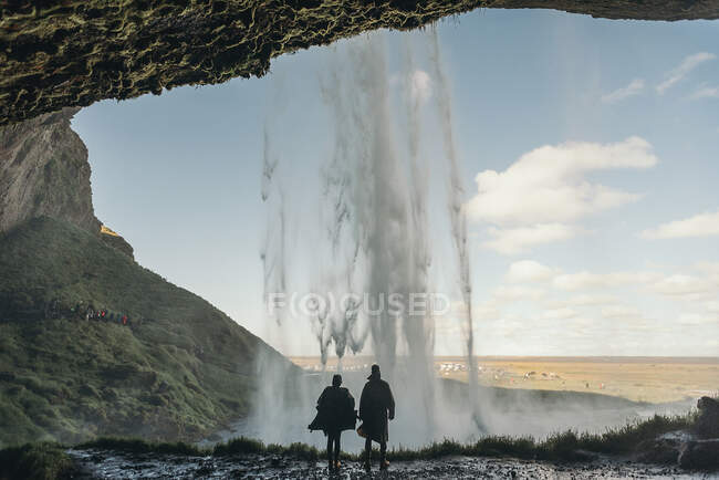 Вид ззаду чоловік і жінка, що стоїть біля водоспаду в схилі пагорба . — стокове фото