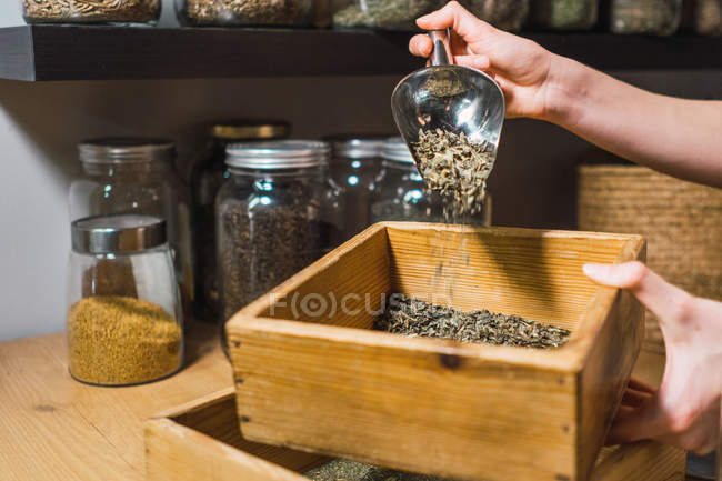 Mains humaines jetant des épices dans la boîte dans le magasin — Photo de stock