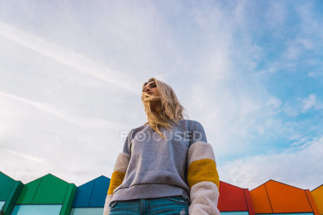 Stylische blonde Frau steht vor modernen, hellen Häusern — Stockfoto