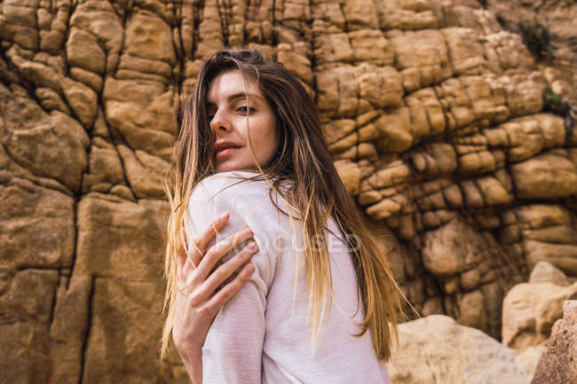 Portrait of young woman posing in front of rough rock — Stock Photo