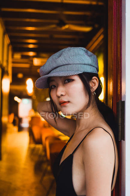 Retrato de elegante asiático jovem mulher inclinada na parede no iluminado restaurante à noite — Fotografia de Stock