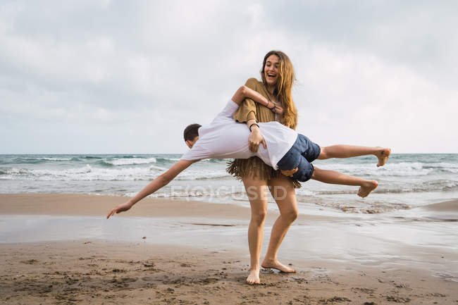 Two laughing teen friends fooling around on seashore in summer — Stock Photo