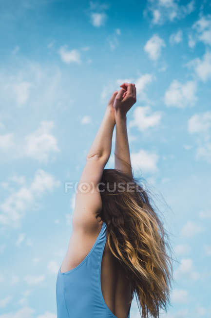 Весела молода жінка в блакитному купальнику стоїть на блакитному небі — стокове фото