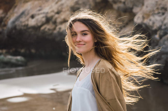 Портрет девушки с длинными каштановыми волосами, стоящей на пляже — стоковое фото