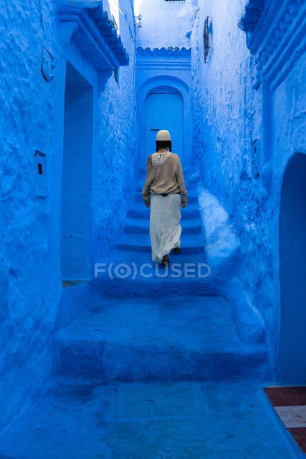 Frau geht auf Treppe auf blau gefärbter Straße, Marokko — Stockfoto