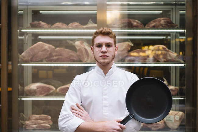 Retrato de Chef de pie con los brazos cruzados y sartén en el restaurante - foto de stock