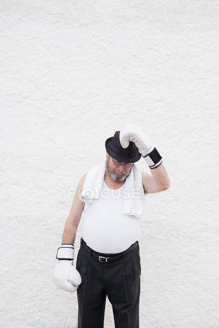 Erwachsener Mann mit Hut und weißen Boxhandschuhen an rauer Wand. — Stockfoto