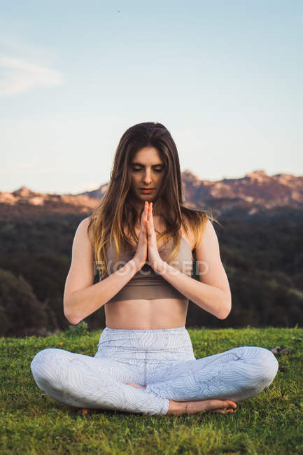 Mujer haciendo yoga sobre hierba en la naturaleza - foto de stock