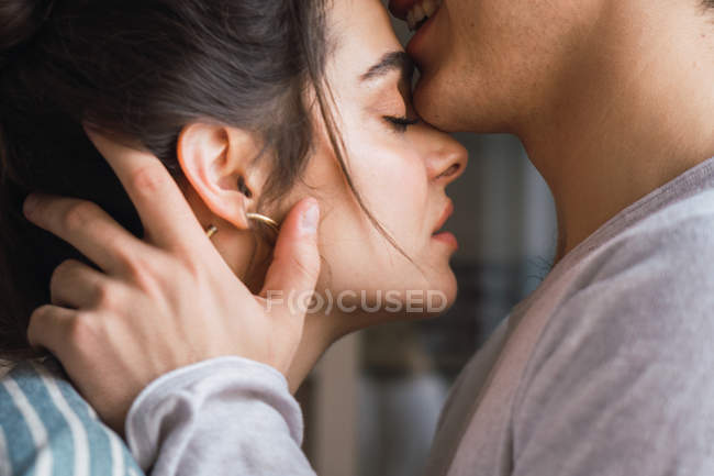 Sensual pareja en pijama de pie uno junto al otro en casa - foto de stock
