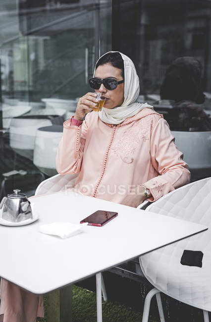 Mujer marroquí con hijab y vestido árabe típico beber té en la cafetería - foto de stock