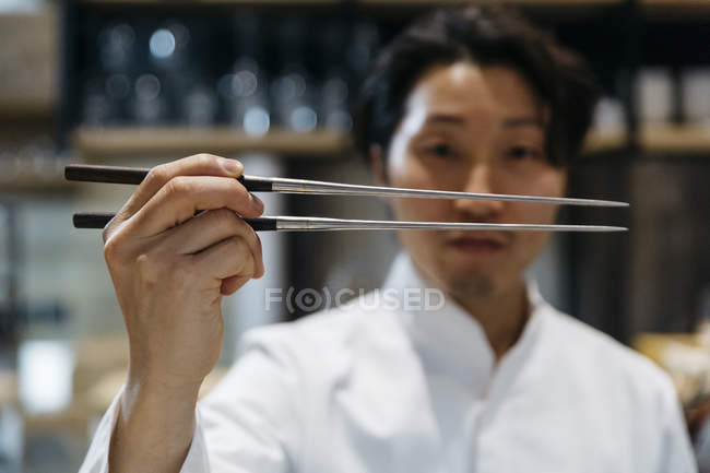 Gros plan du chef japonais tenant des baguettes — Photo de stock