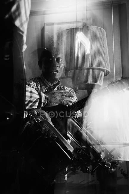 Músico maduro tocando guitarra em boate, tiro preto e branco com longa exposição — Fotografia de Stock