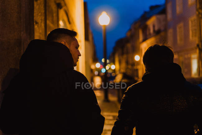 Два чоловіки ходять разом на освітленій вулиці вночі — стокове фото