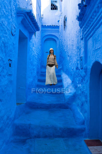 Женщина идет по голубой окрашенной улице, Марокко — стоковое фото
