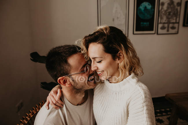 Homem e mulher felizes sentados e abraçando em casa juntos — Fotografia de Stock